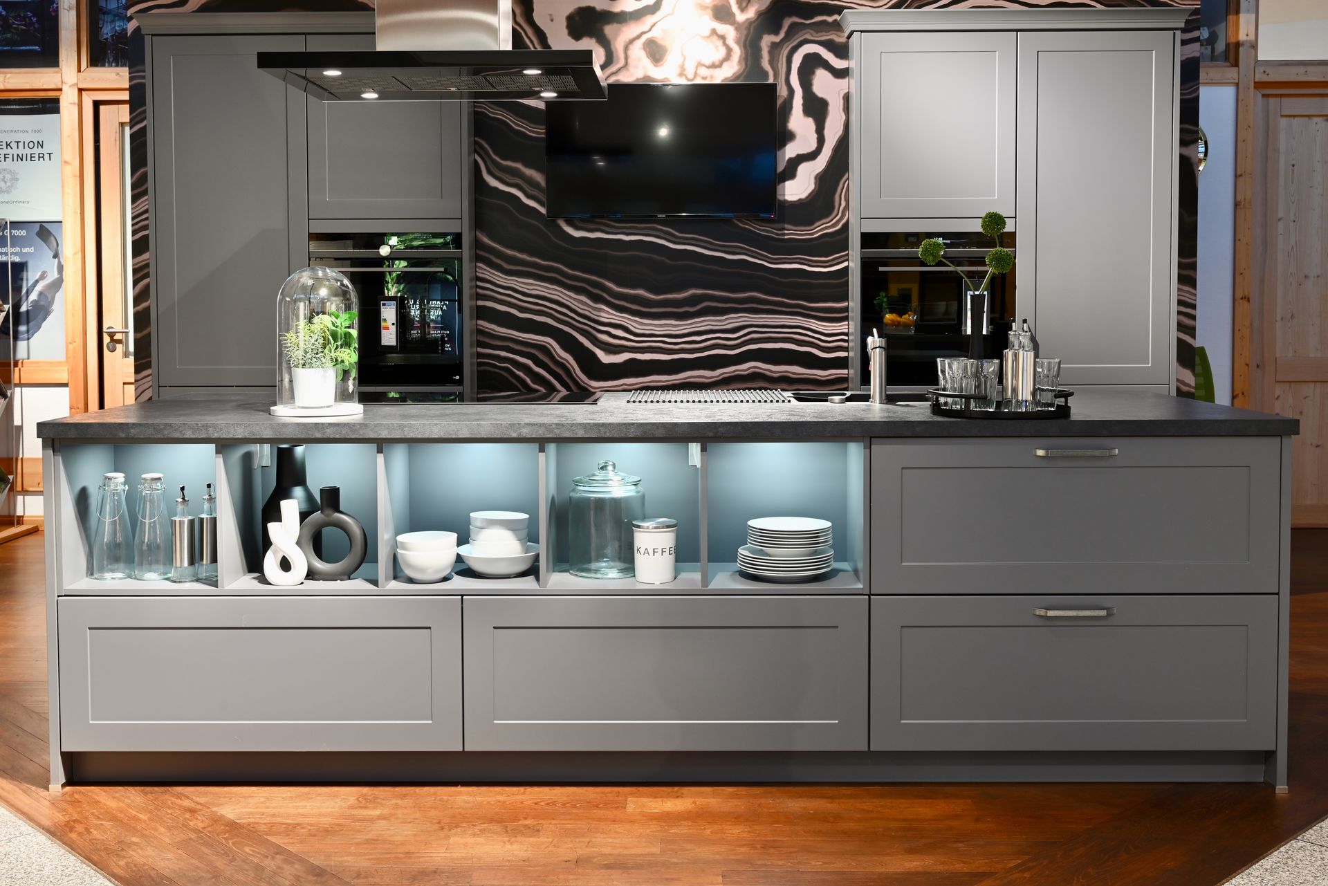 Eine Küche mit einer großen Insel in der Mitte und einer Marmorwand dahinter.