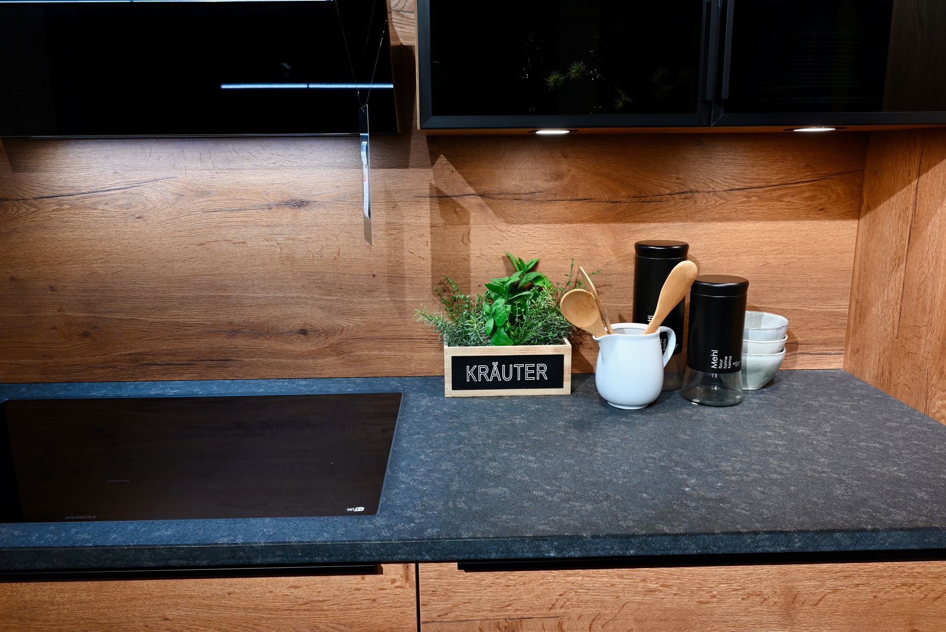 Eine Küchentheke mit Herd und Backofen und Küchenutensilien darauf.