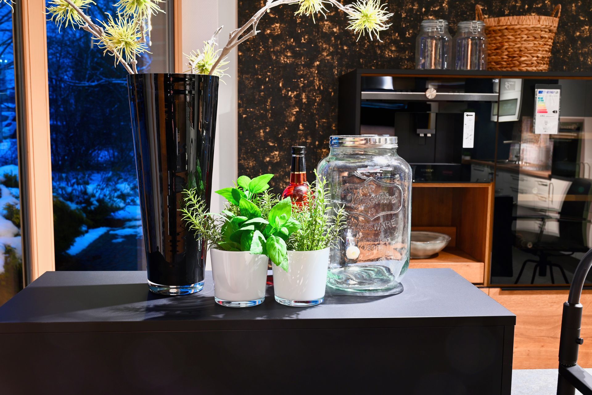 Ein Tisch mit einer Vase, Krügen und Topfpflanzen darauf.