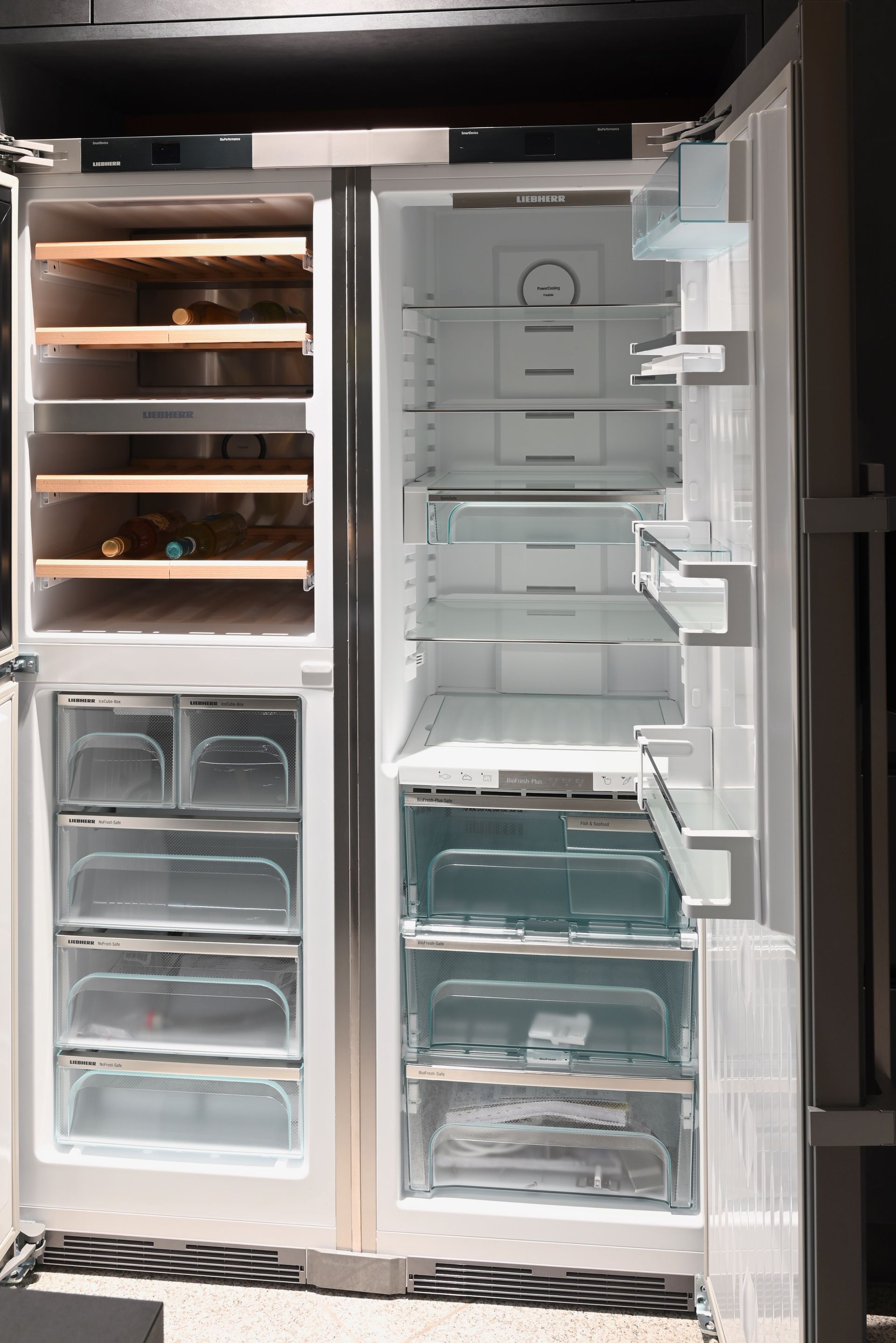 Ein leerer Kühlschrank mit offener Tür und einem Weinregal.