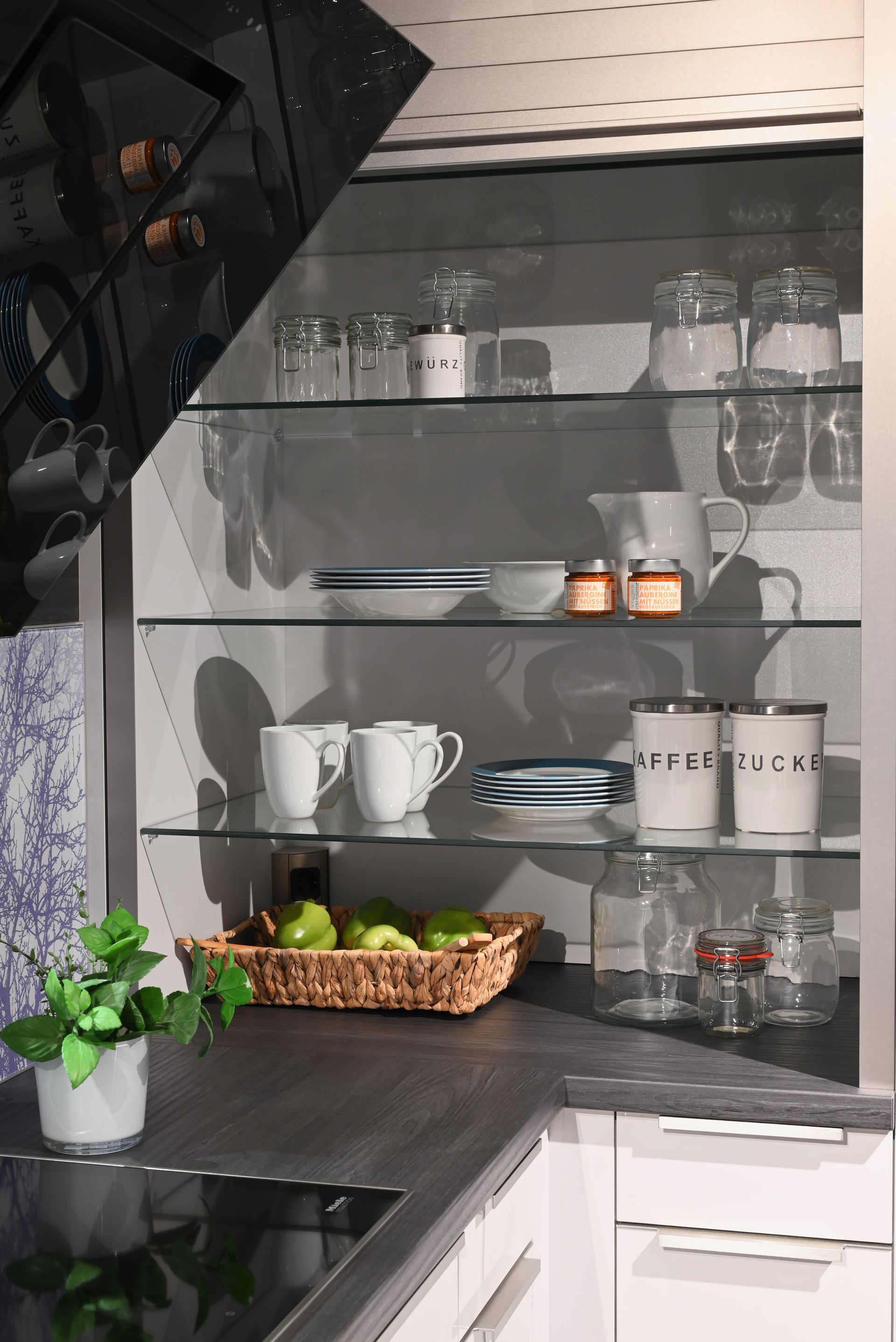 Eine Küche mit vielen Glasregalen und einem Obstkorb auf der Theke.