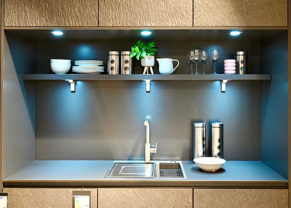 Eine Küche mit einer Spüle und einem Regal mit Tellern und Gläsern darauf.