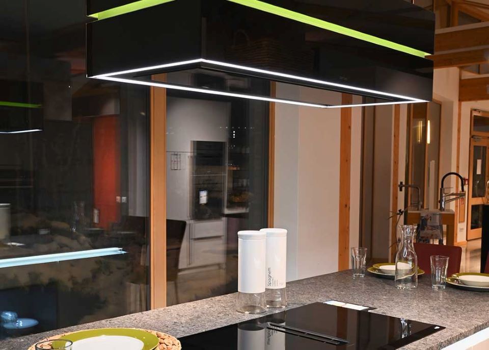 Eine Küche mit einem schwarzen Herd und einem grünen Licht, das von der Decke hängt.