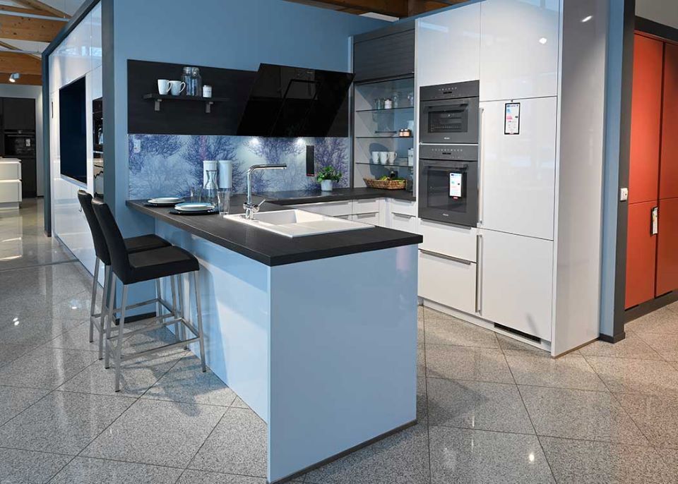 Eine Küche mit weißen Schränken und schwarzen Arbeitsplatten in einem Ausstellungsraum.