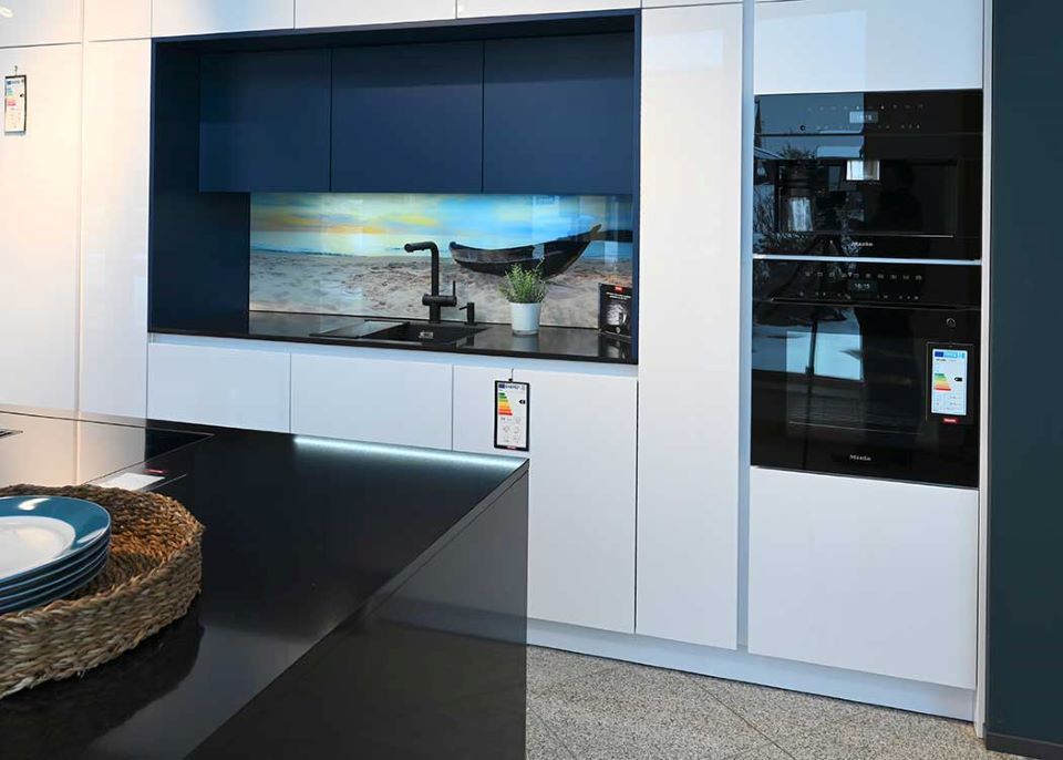 Eine Küche mit weißen Schränken und einer schwarzen Arbeitsplatte