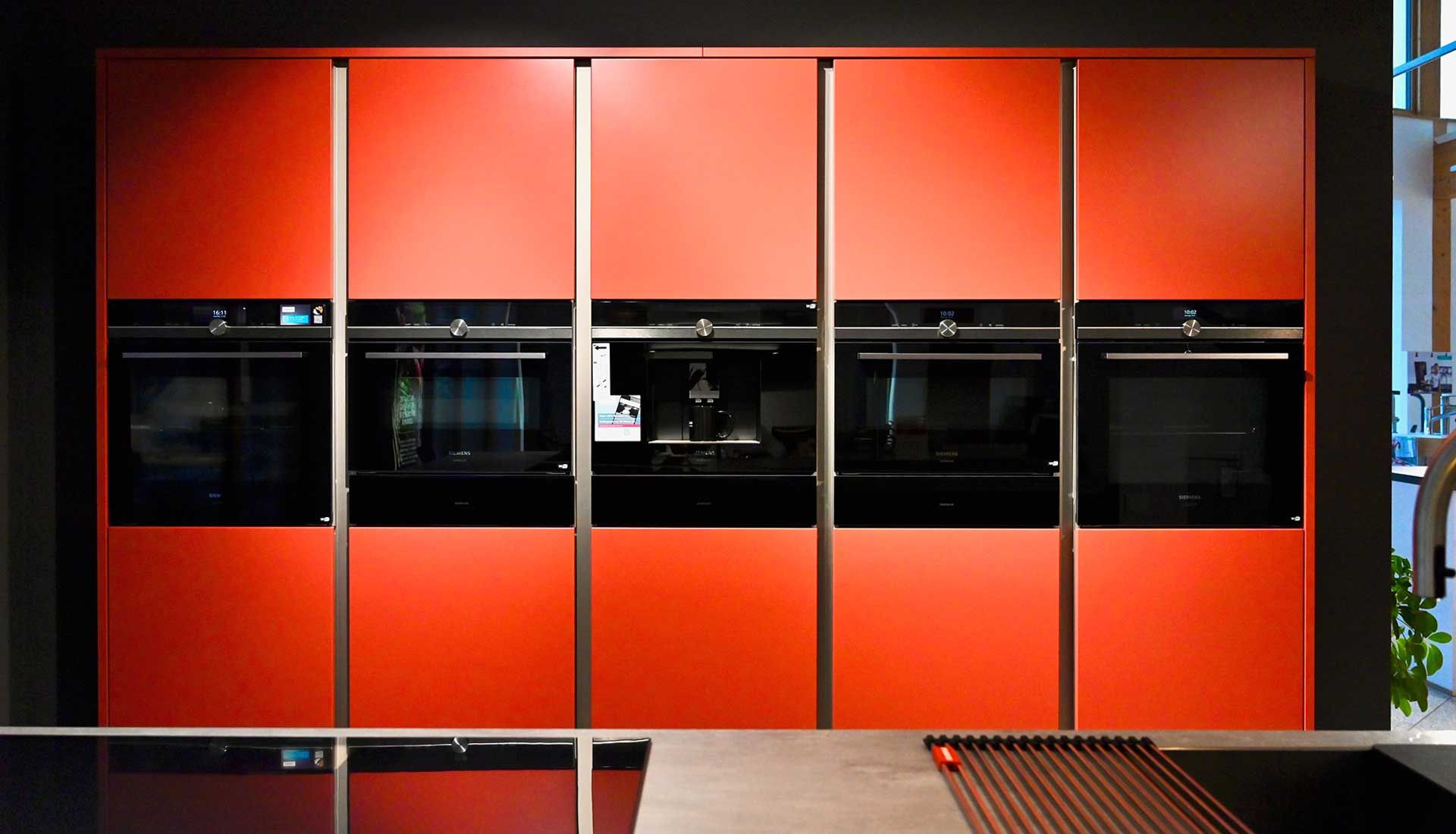 Eine Küche mit roten Schränken und schwarzen Geräten