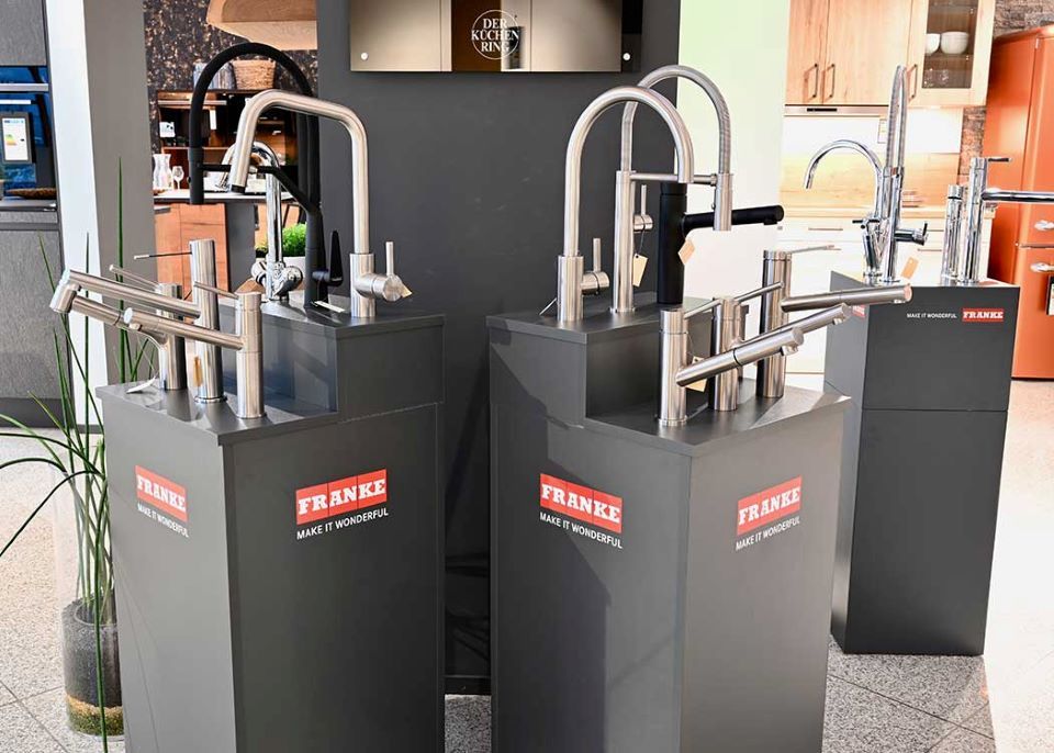 Eine Ausstellung von Edelstahl-Spültischarmaturen in einer Küche.