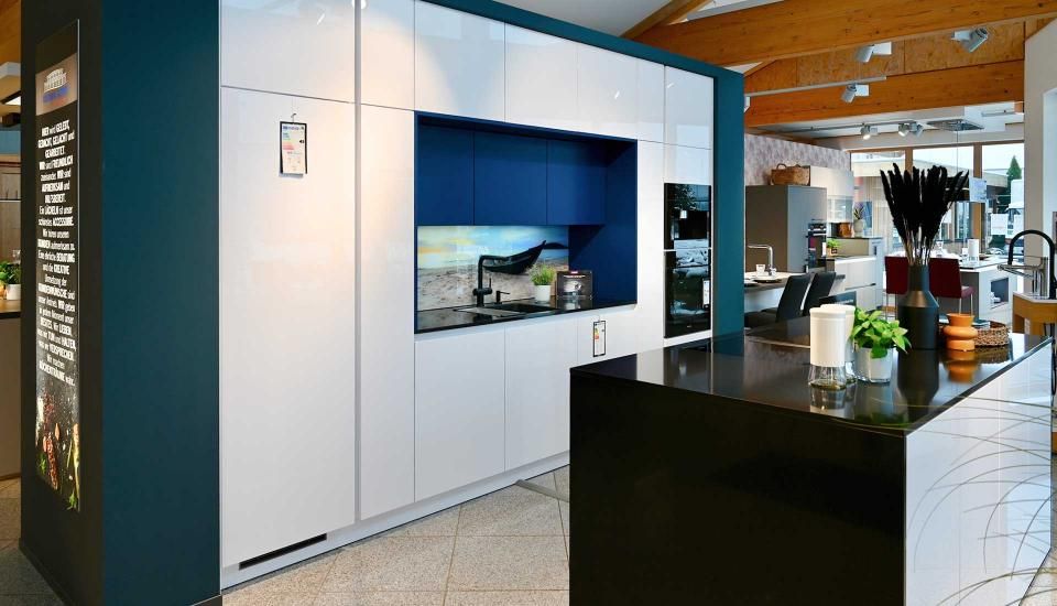 Eine Küche mit blauen und weißen Schränken und einer schwarzen Insel