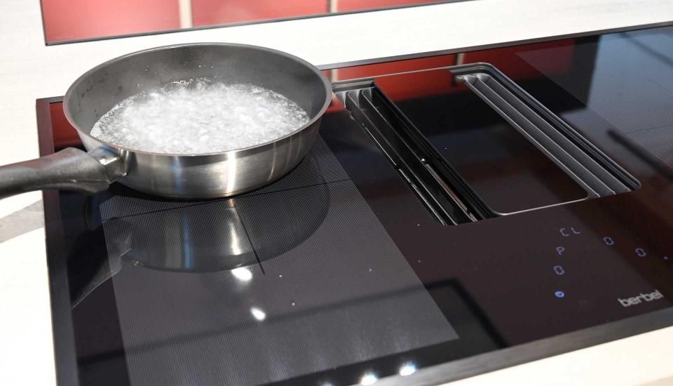 Auf einem Herd steht ein Topf mit kochendem Wasser.