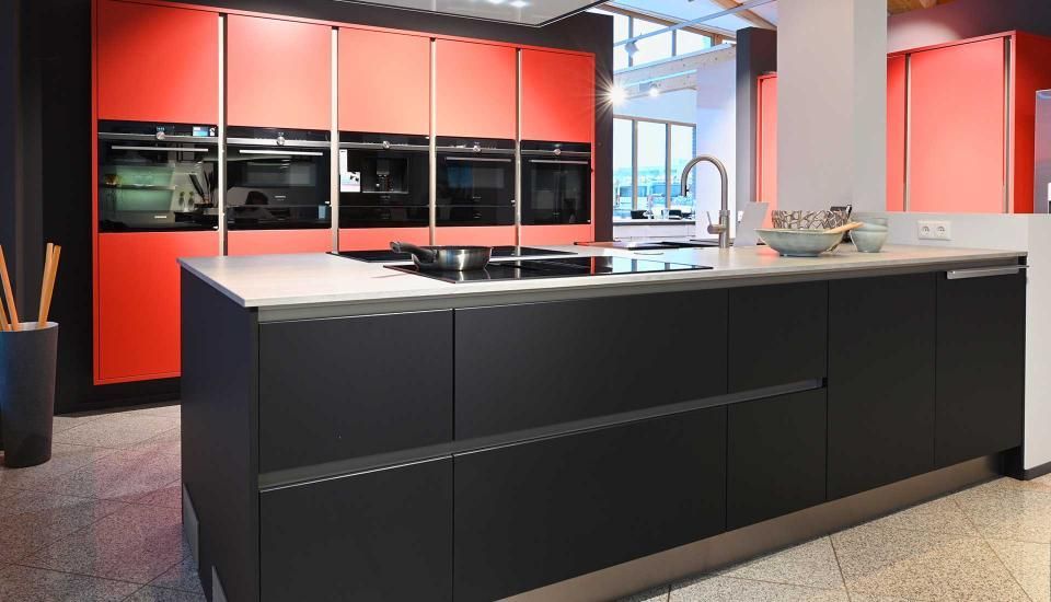 Eine Küche mit roten und schwarzen Schränken und einer großen Insel in der Mitte.