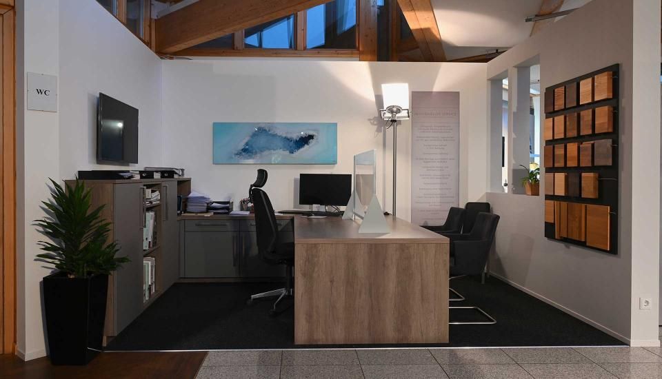 Ein Zimmer mit einem Schreibtisch und Stühlen und einem Computer darauf.