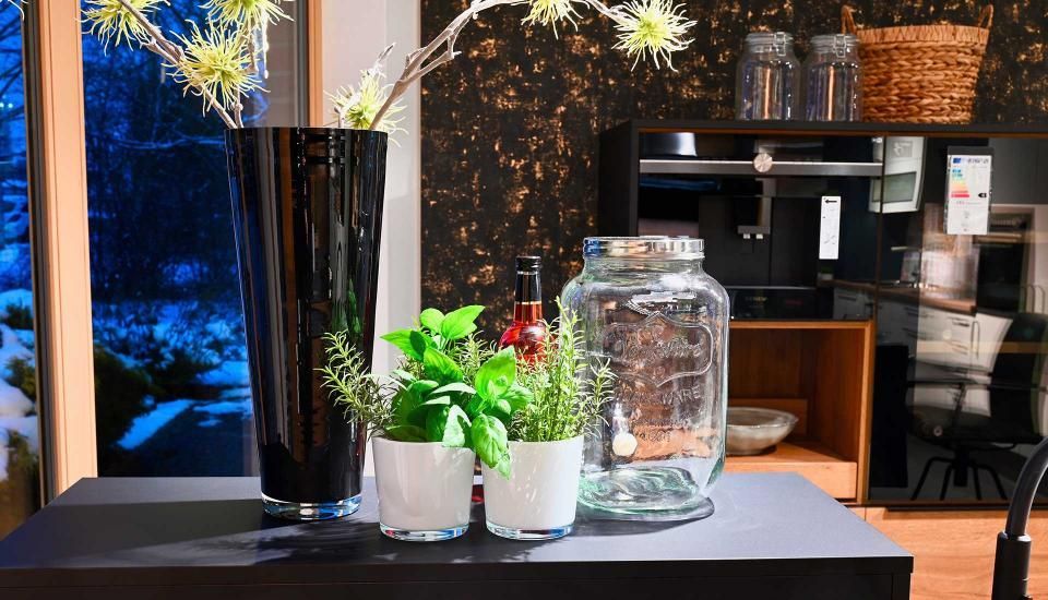 Ein Tisch mit einer Vase, Krügen und Topfpflanzen darauf.