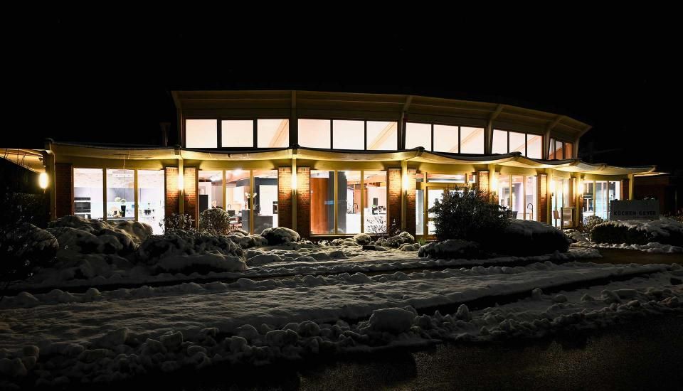 Ein großes Gebäude mit vielen Fenstern ist nachts beleuchtet.