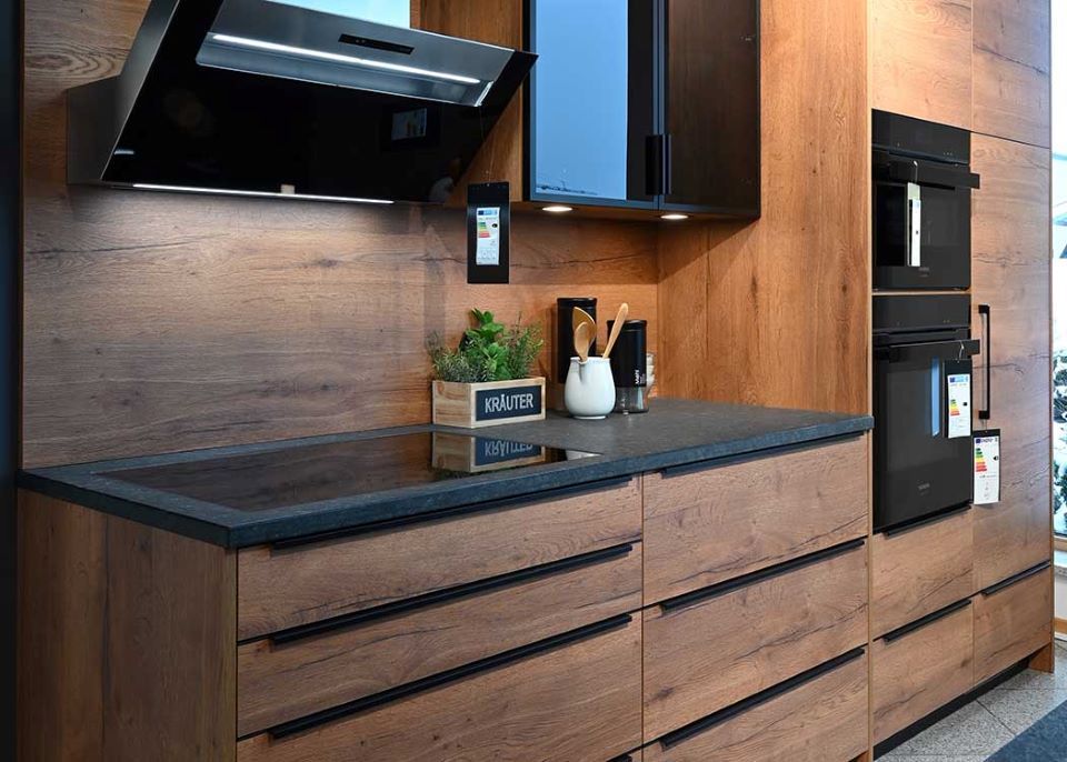 Eine Küche mit Holzschränken und schwarzen Geräten.