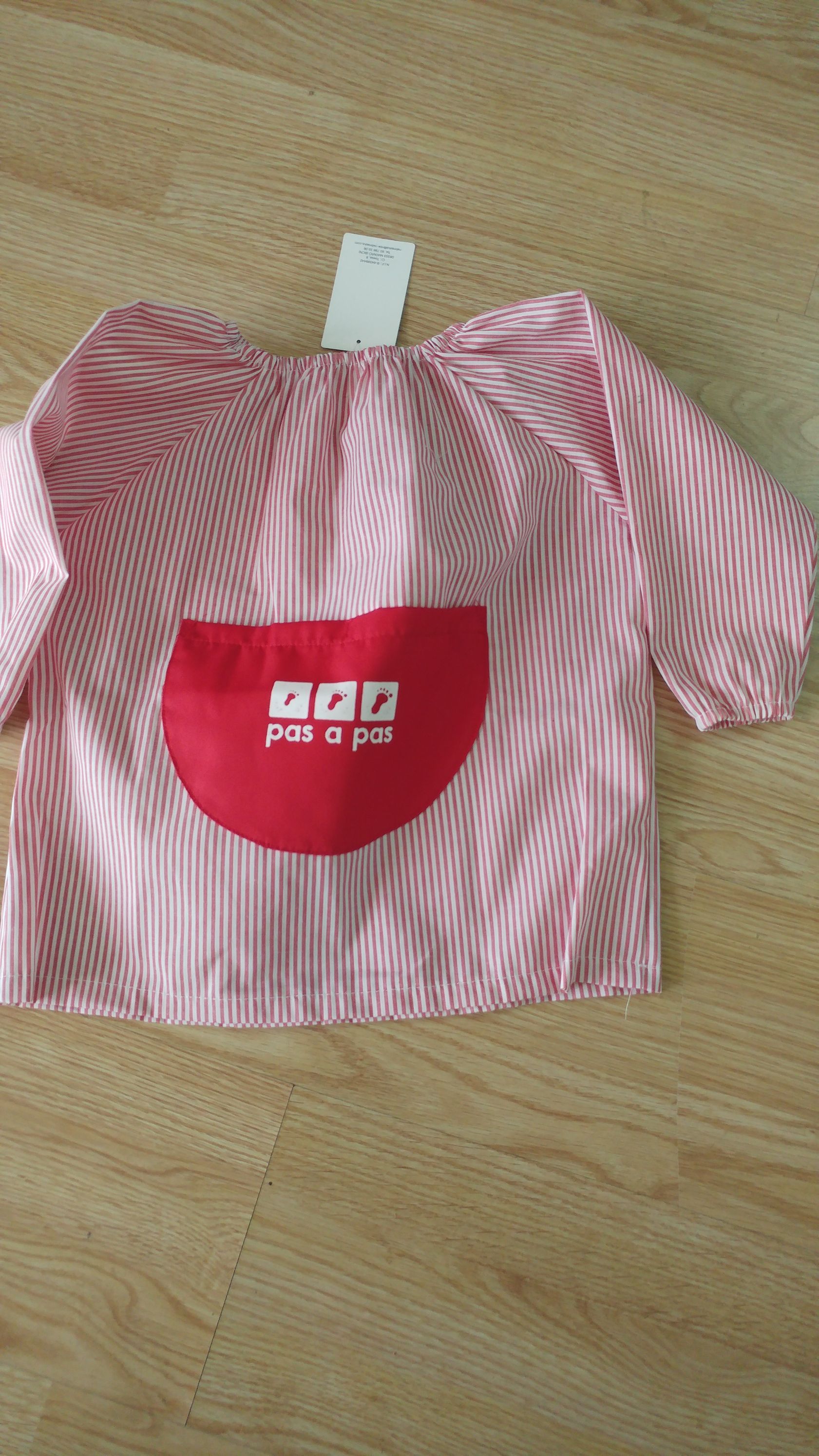 Una camisa de rayas rojas y blancas con un bolsillo rojo está sobre una mesa de madera.