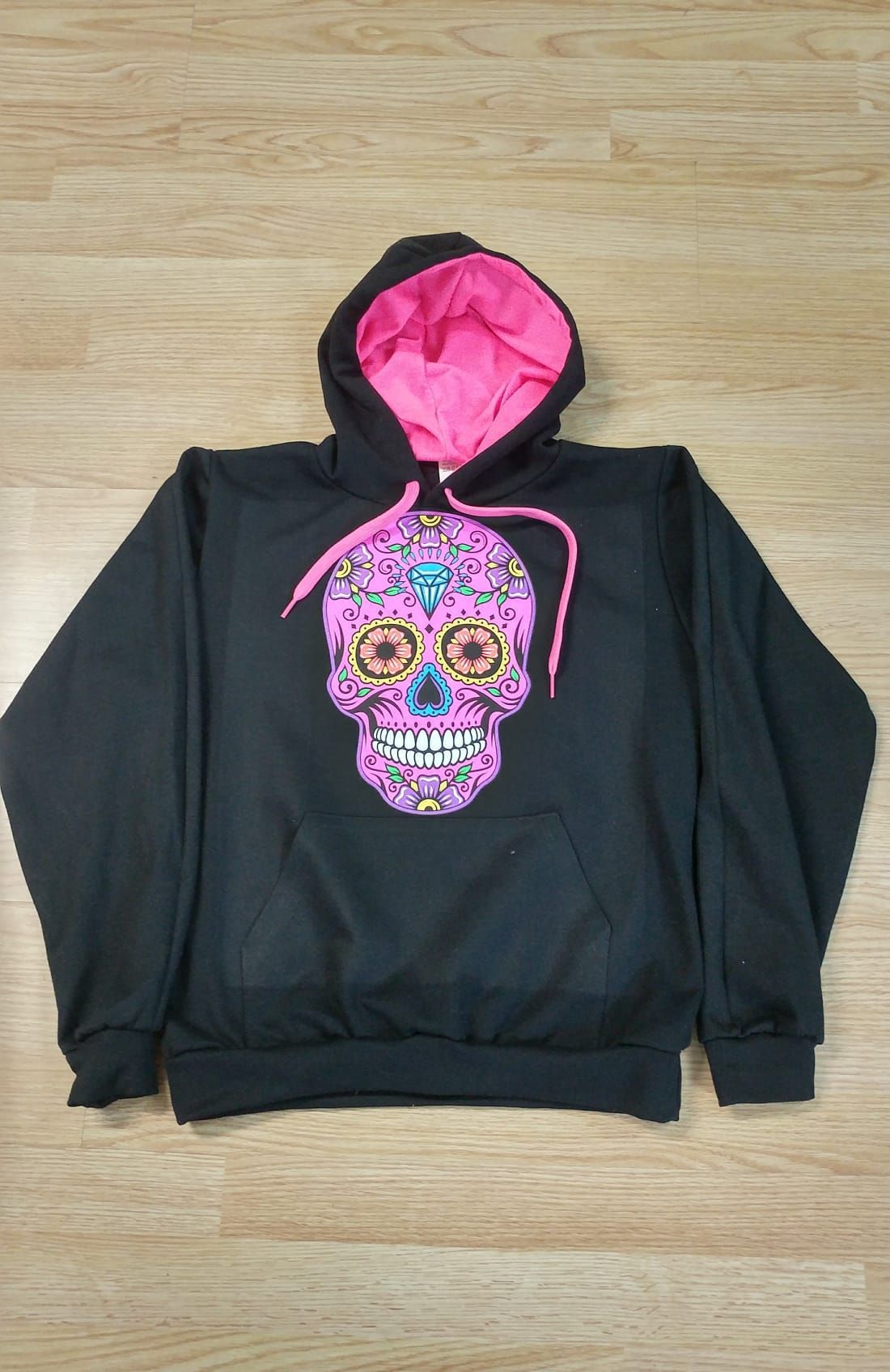 Una sudadera con capucha negra con una calavera de azúcar rosa encima.