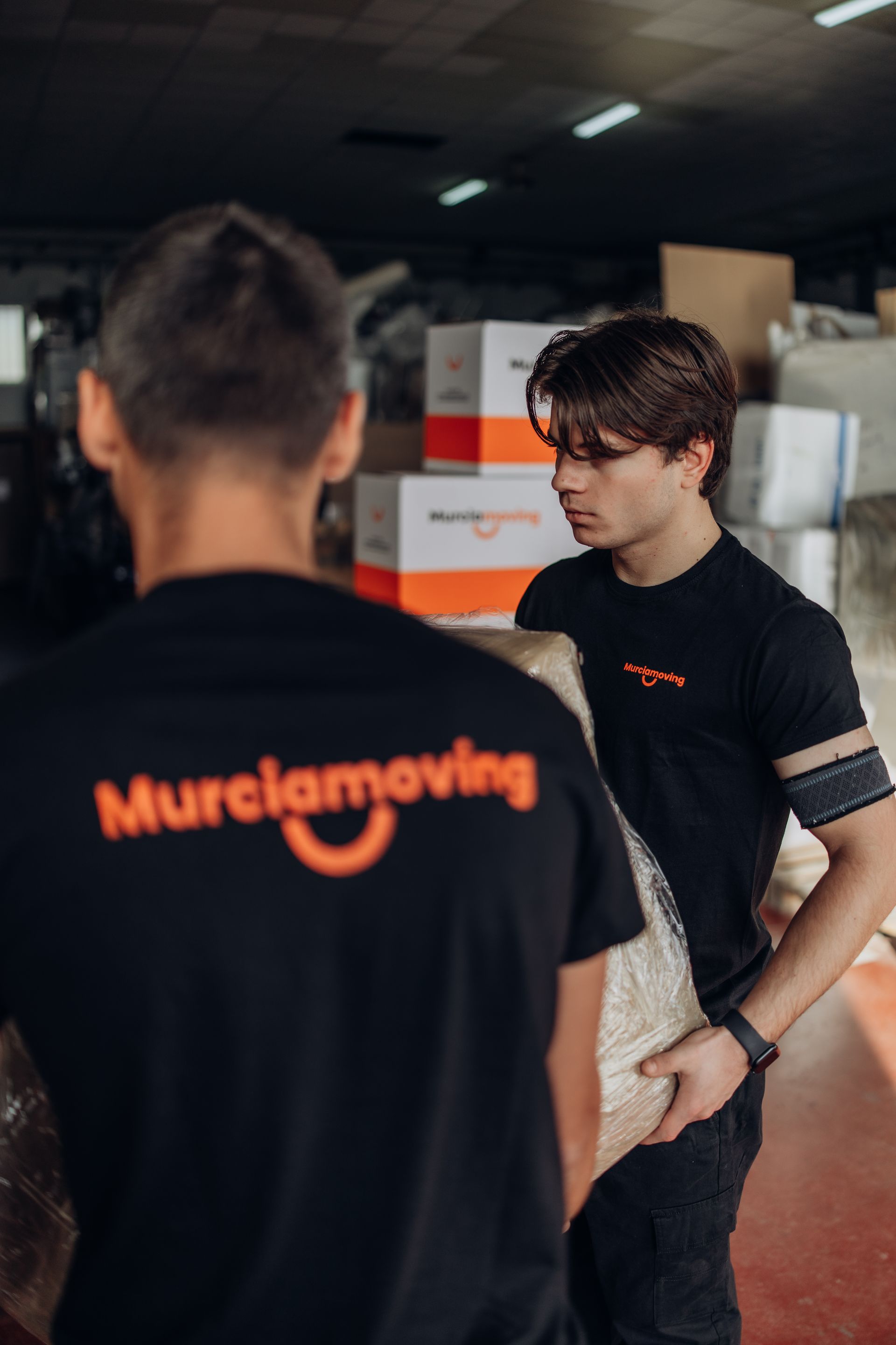 Mano que alcanza una caja de cartón en un estante de un almacén.