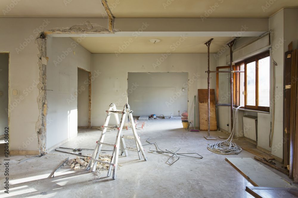Innenansicht während der Renovierung; Leiter, Stützbalken, offene Türen, freiliegende Wände, Baumaterialien und ein Fenster.
