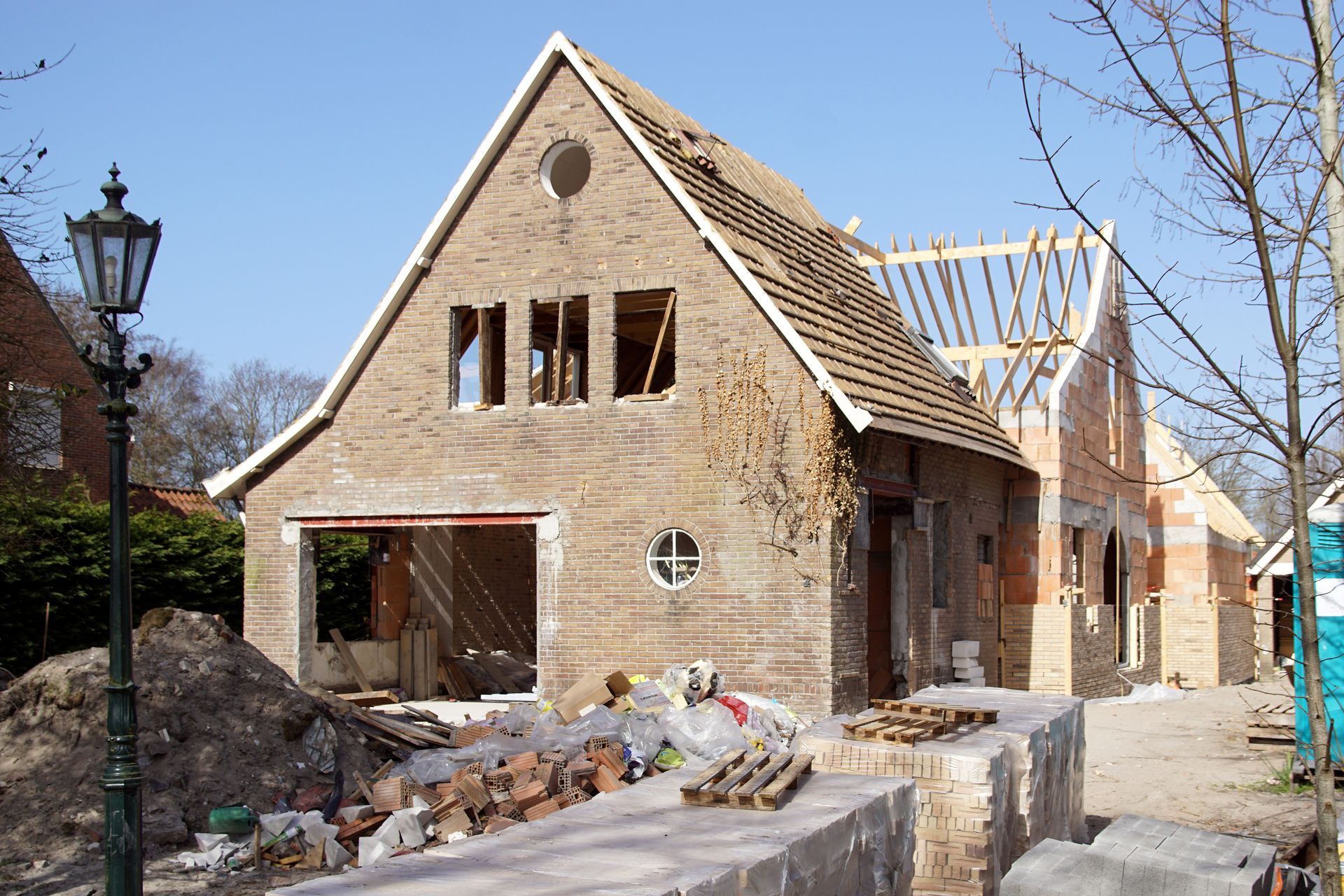 Maison en briques partiellement construite, avec charpente de toit et matériaux de construction à l'extérieur.