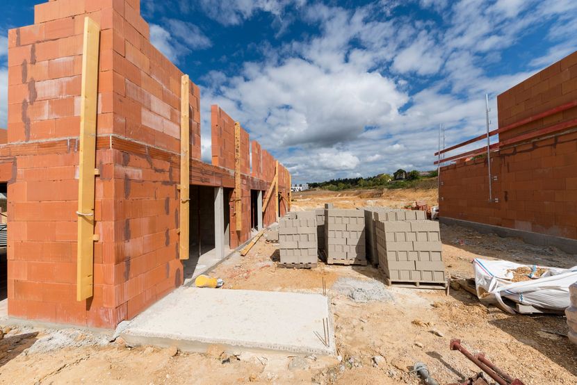 Maison en briques partiellement construite, avec des parpaings empilés et une dalle de béton.