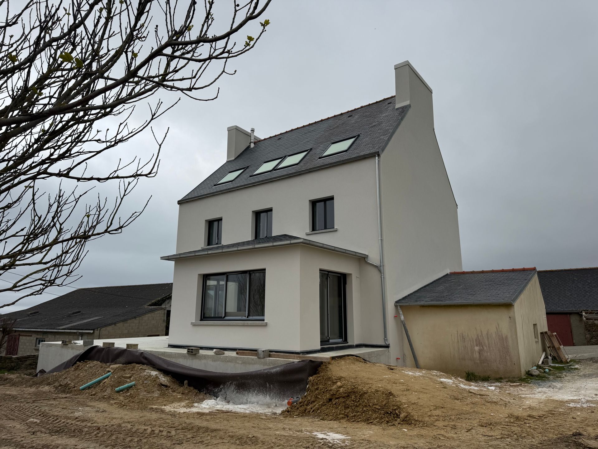 Maison jaune de deux étages partiellement rénovée, avec murs en briques apparentes et échafaudages en façade.