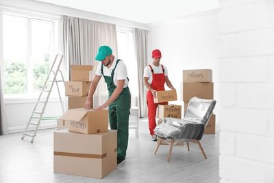 Dos hombres están moviendo cajas en una sala de estar.