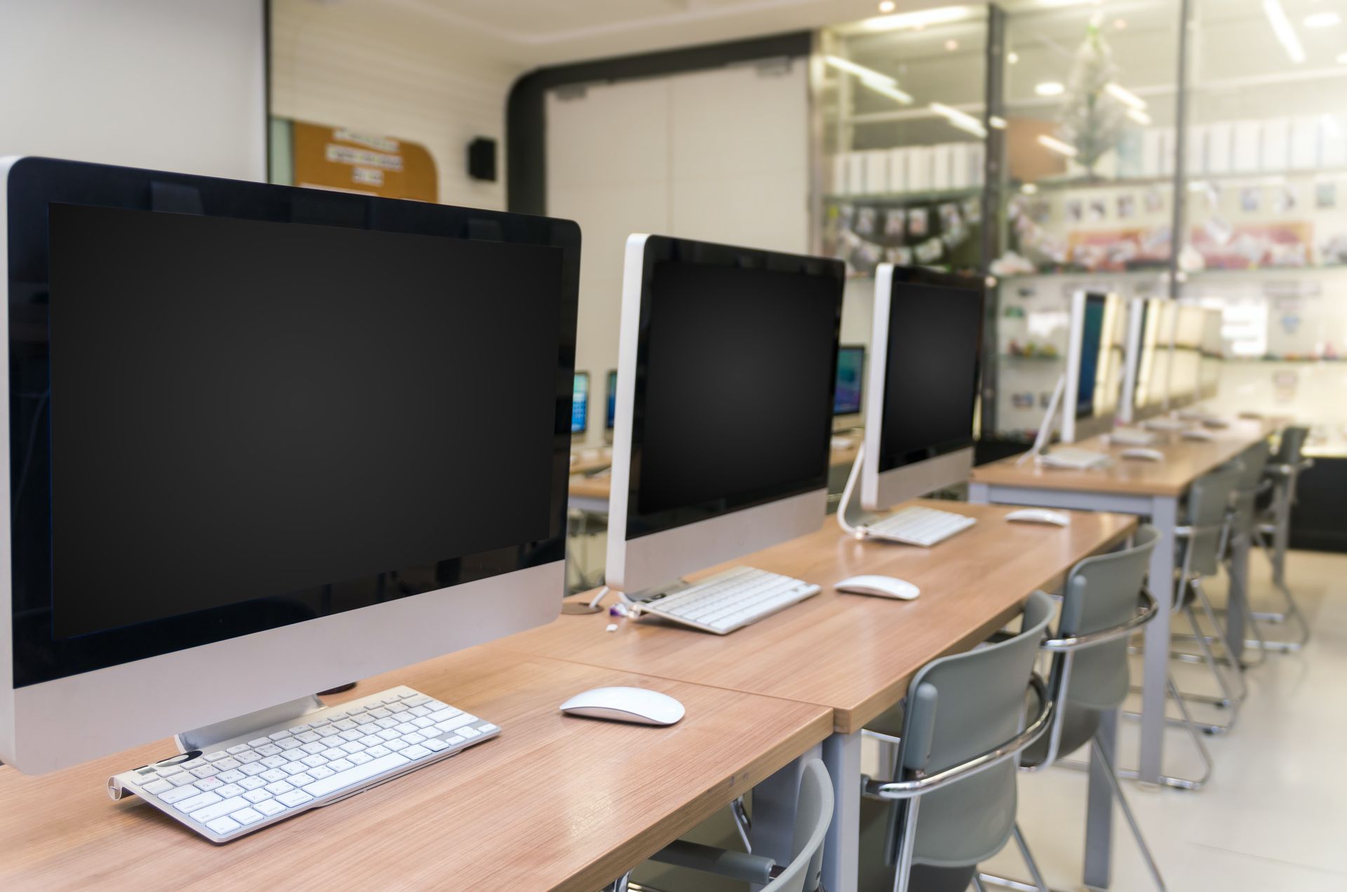 Una fila de computadoras colocadas sobre escritorios de madera en un laboratorio de computación.