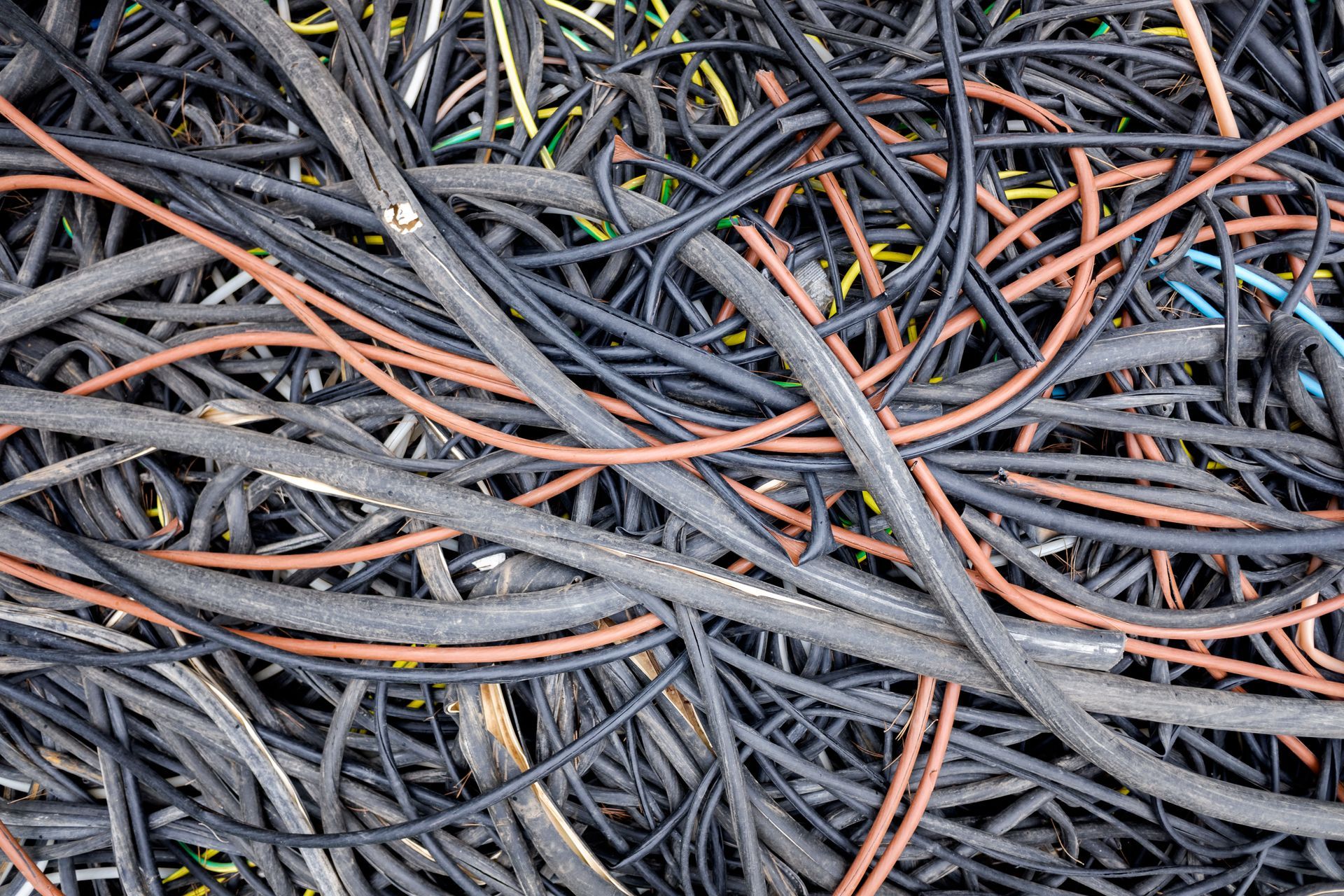 Un amas emmêlé de câbles et de fils électriques gris, noirs et orange.