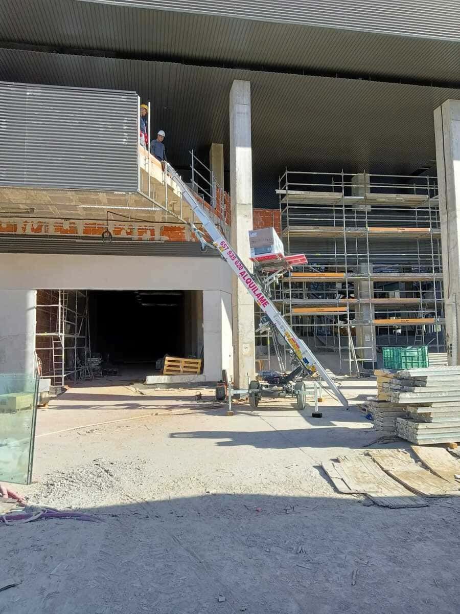 Obra con una persona en un elevador. Andamios, paredes sin terminar y escombros visibles.