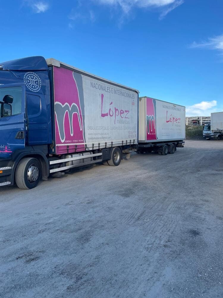 Parte trasera de un camión cargado con varios artículos blancos empaquetados, posiblemente para una mudanza o entrega.