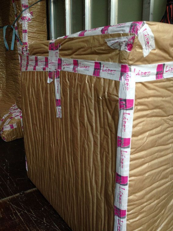 Un artículo grande y empaquetado, envuelto en papel marrón y asegurado con cinta rosa y blanca; en el interior.