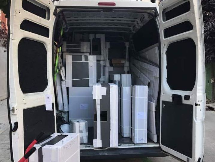 Furgoneta blanca abierta llena de muebles embalados, listos para ser entregados.