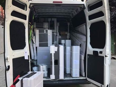 Furgoneta blanca abierta llena de muebles embalados, listos para ser entregados.