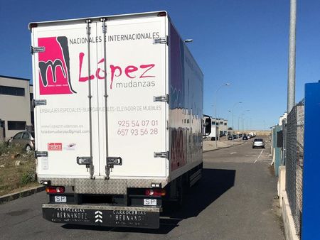 Parte trasera de un camión de mudanzas blanco, logo