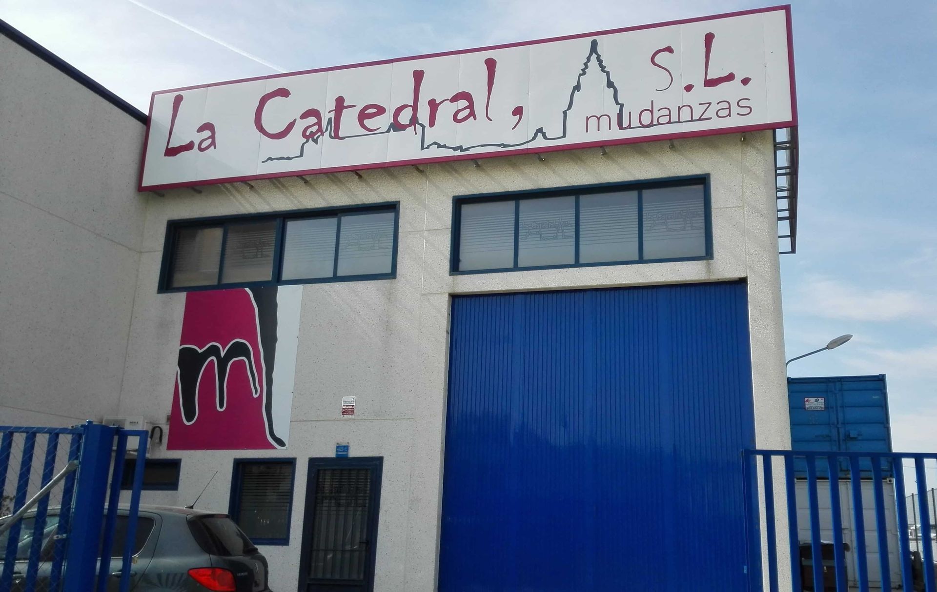 Exterior del edificio: cartel de La Catedral SL sobre puerta azul, logo 