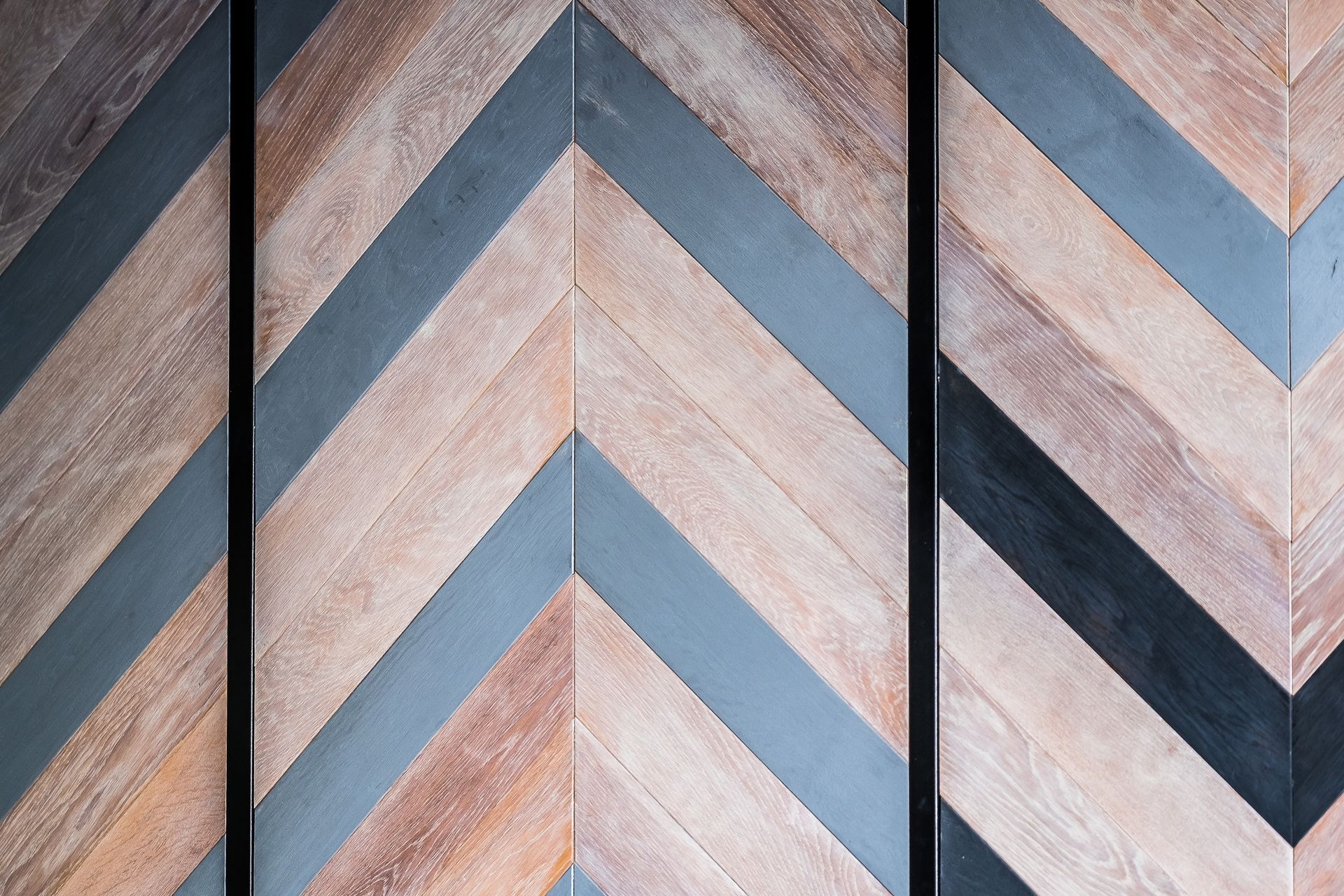 Lambris en bois à motif de chevrons avec des accents gris et noirs.