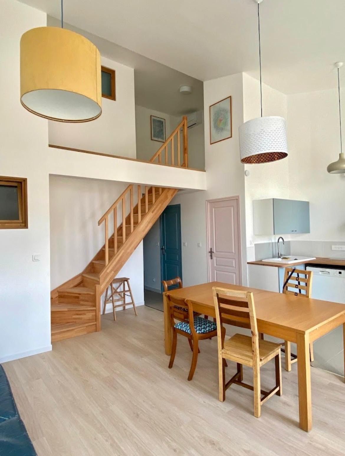 Salon moderne aux couleurs neutres, avec de grandes fenêtres et une télévision intégrée.