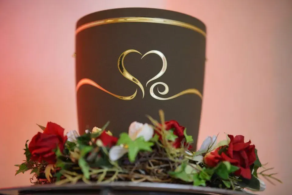 Eine graue moderne Urne mit einem Herz und goldene Verzierungen