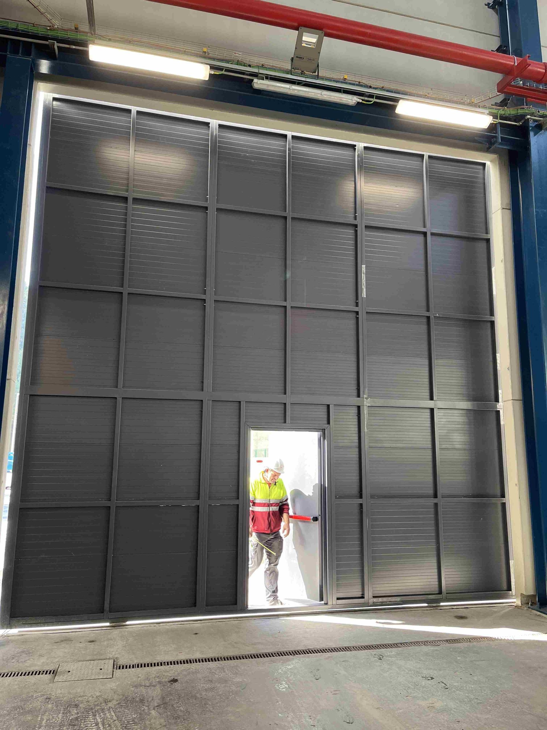 Un hombre está parado frente a una puerta grande en un edificio.