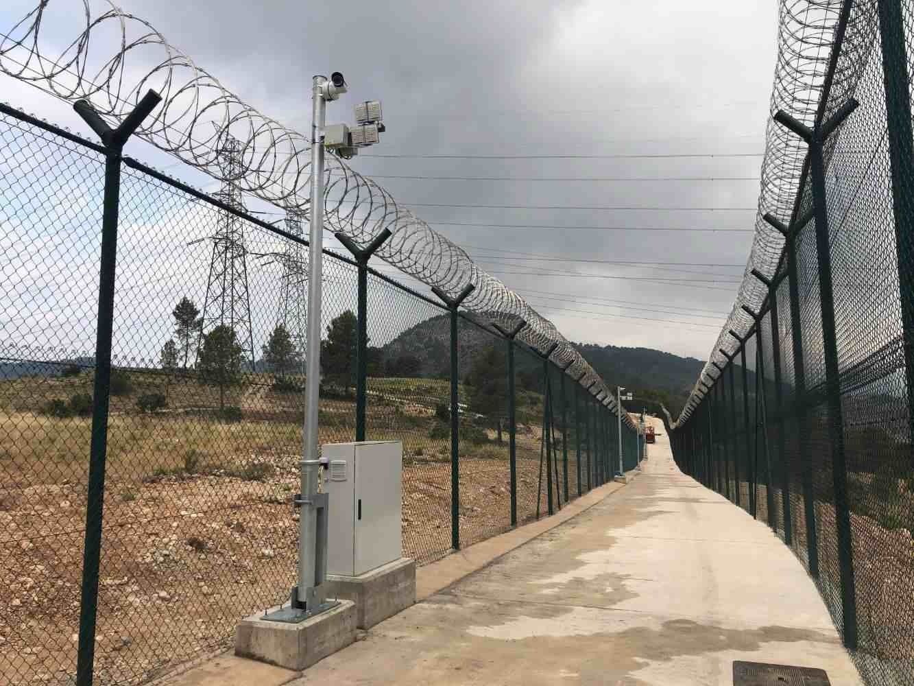 Una cerca de alambre de púas rodea un camino de tierra.