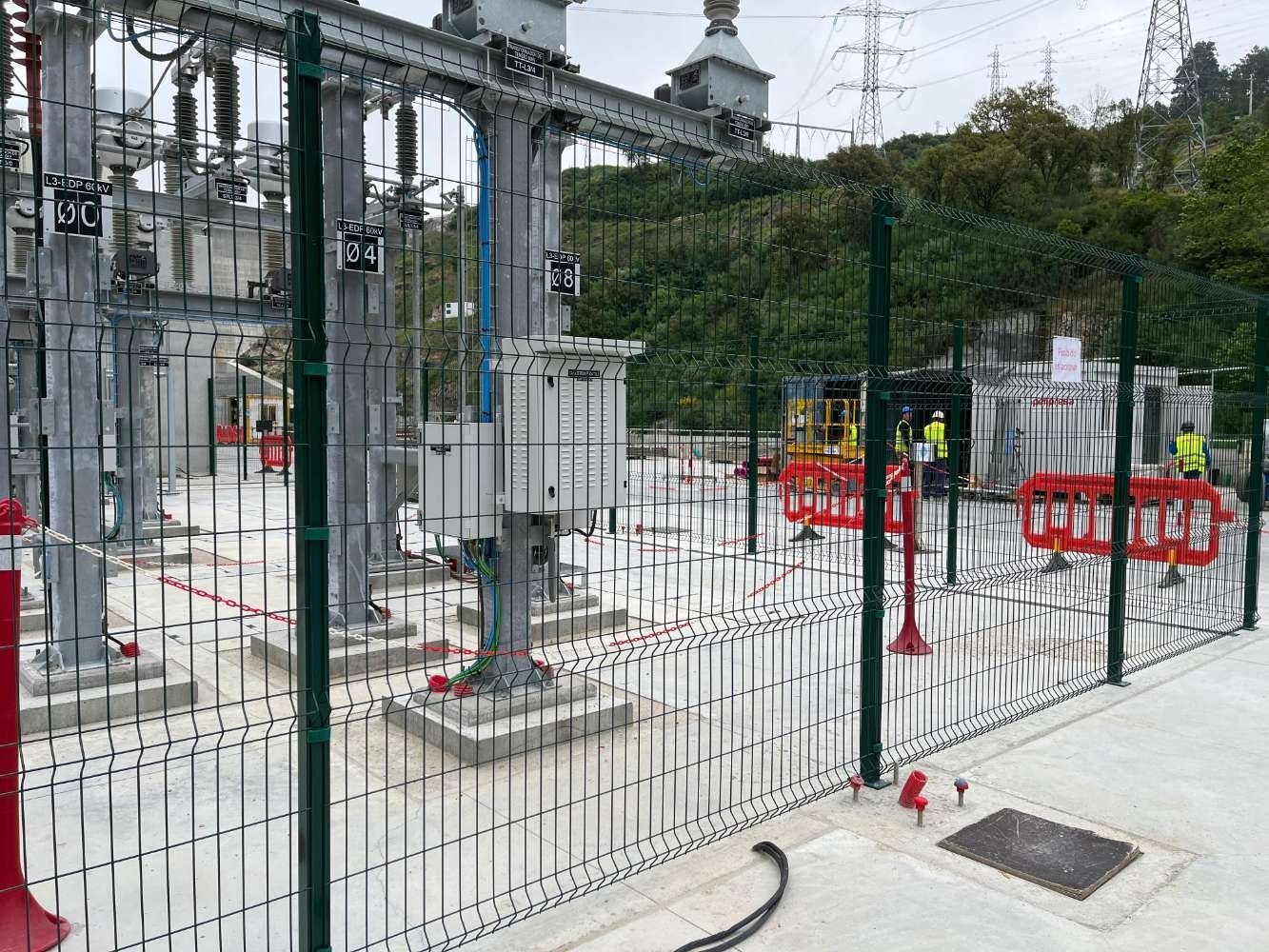 Una valla alrededor de una central eléctrica con mucho equipo eléctrico detrás de ella.