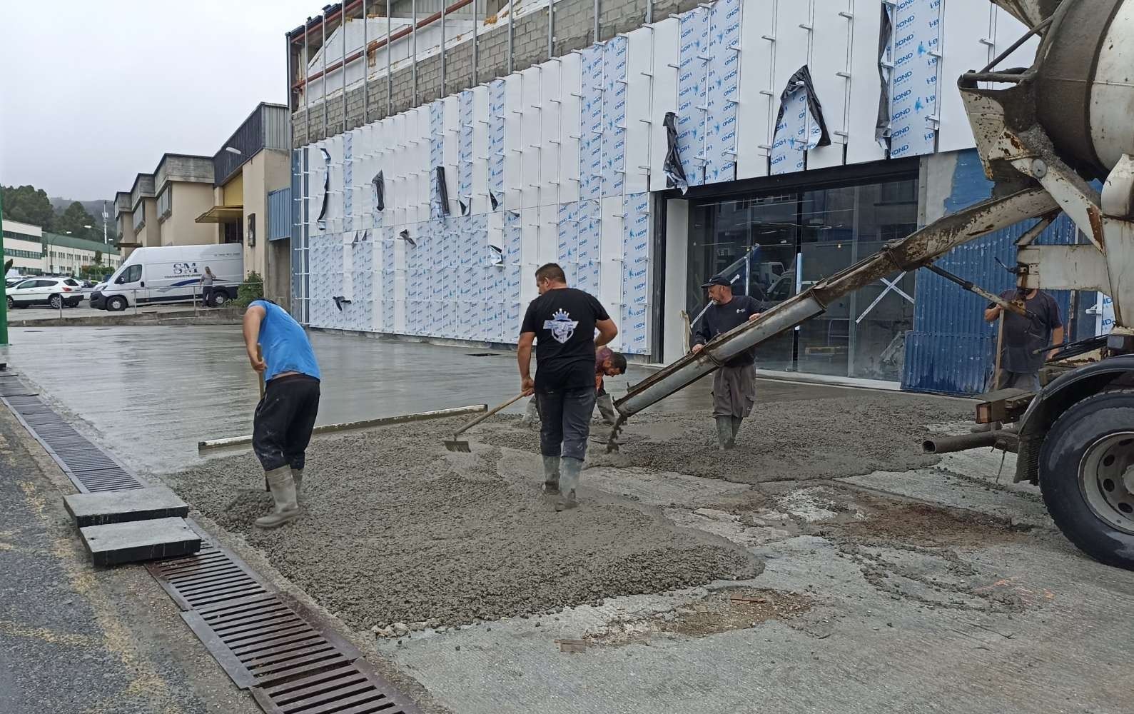 Un grupo de hombres está vertiendo hormigón frente a un edificio.