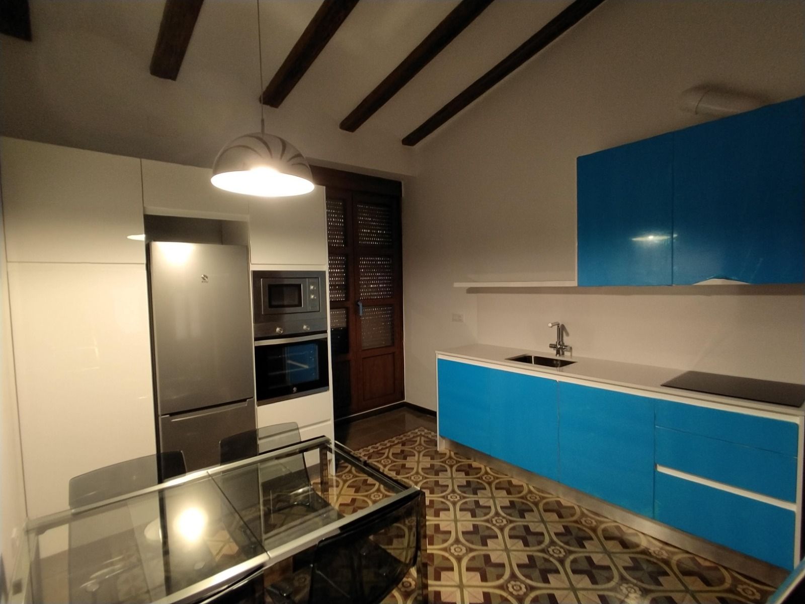 Una cocina con gabinetes azules y una mesa de vidrio.