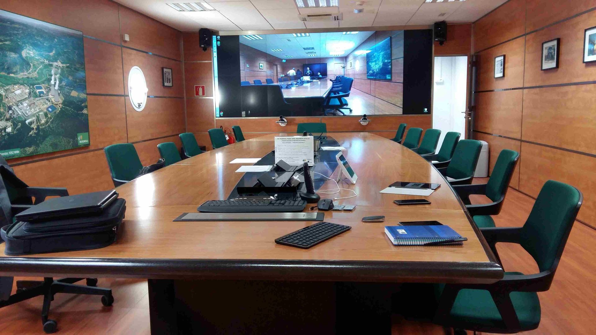Una sala de conferencias con una mesa larga y sillas verdes.