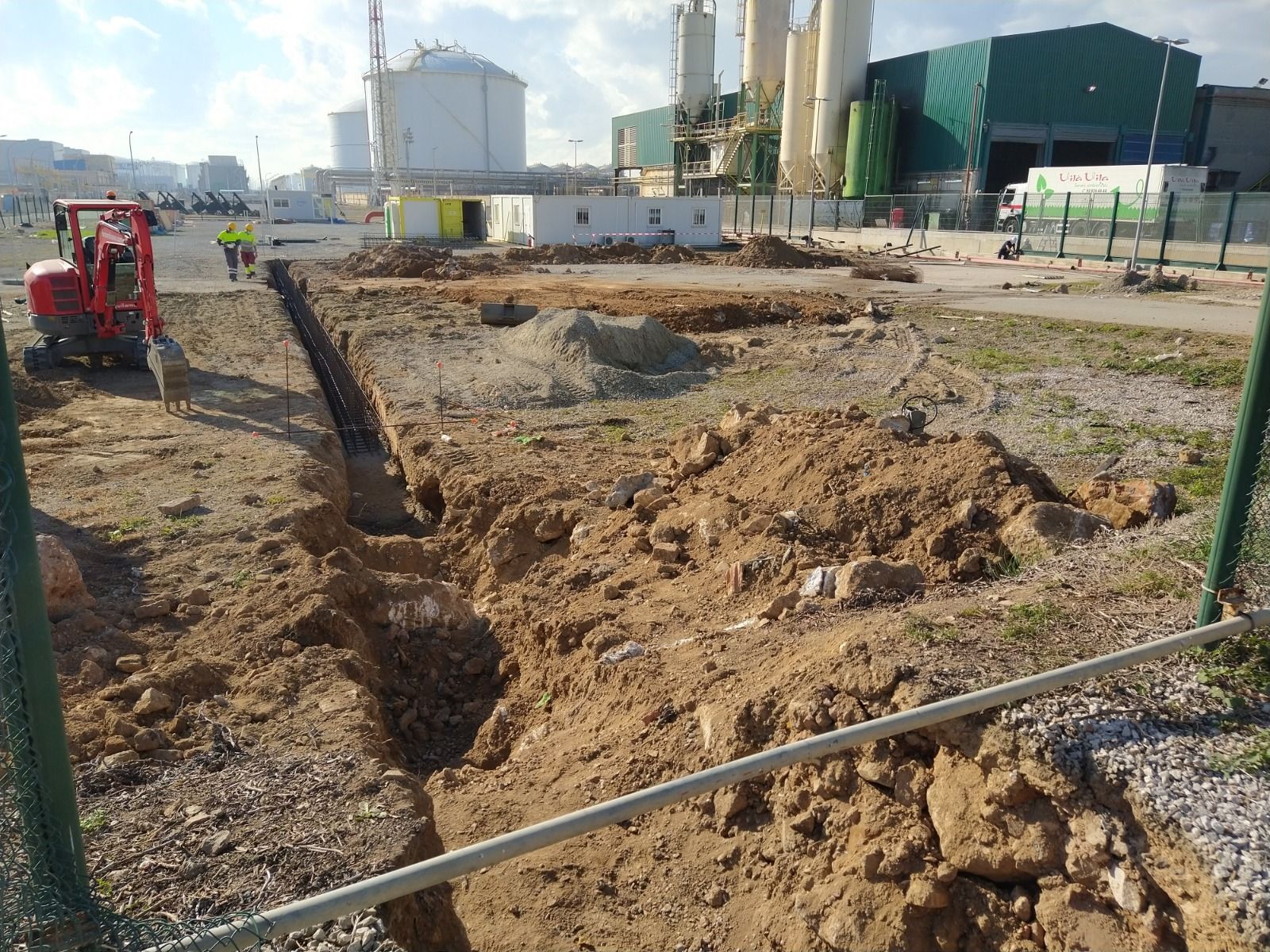 Una excavadora roja está cavando un hoyo en la tierra.