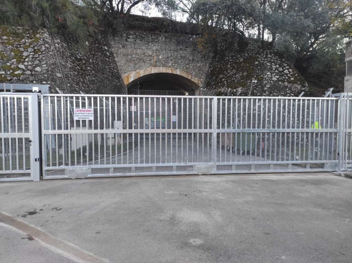Una puerta de metal está cerrada delante de un túnel de piedra.