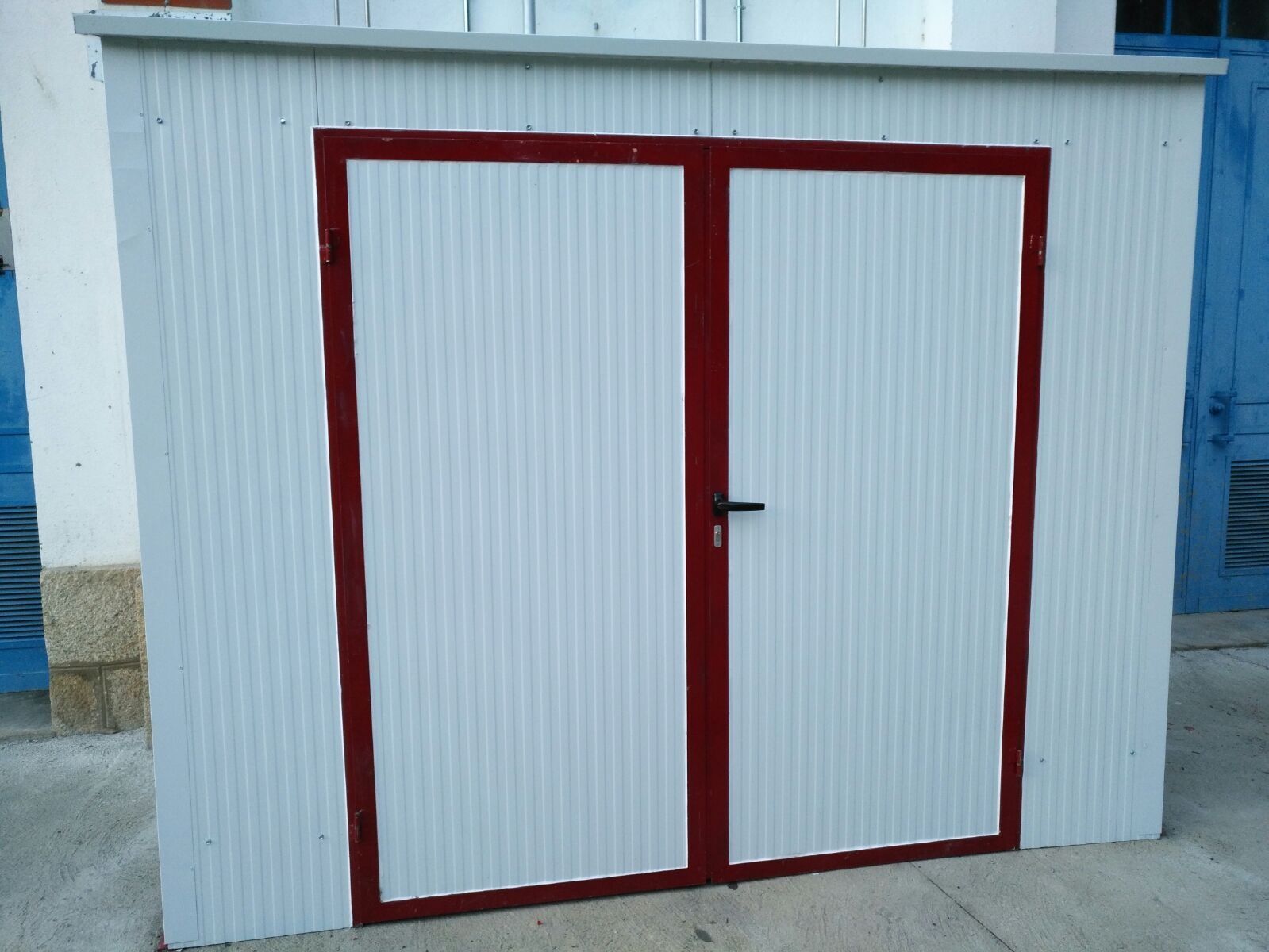 Un edificio blanco con detalles rojos tiene dos puertas.