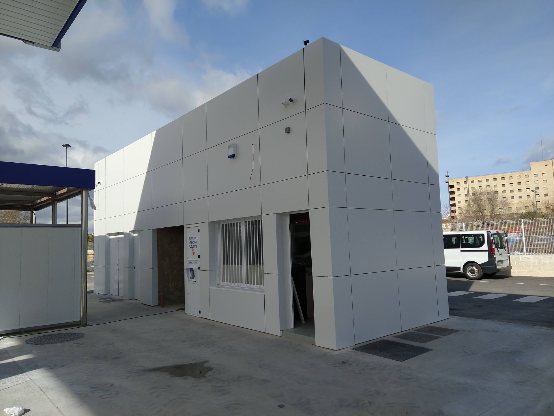 Una camioneta blanca está estacionada frente a un edificio blanco.