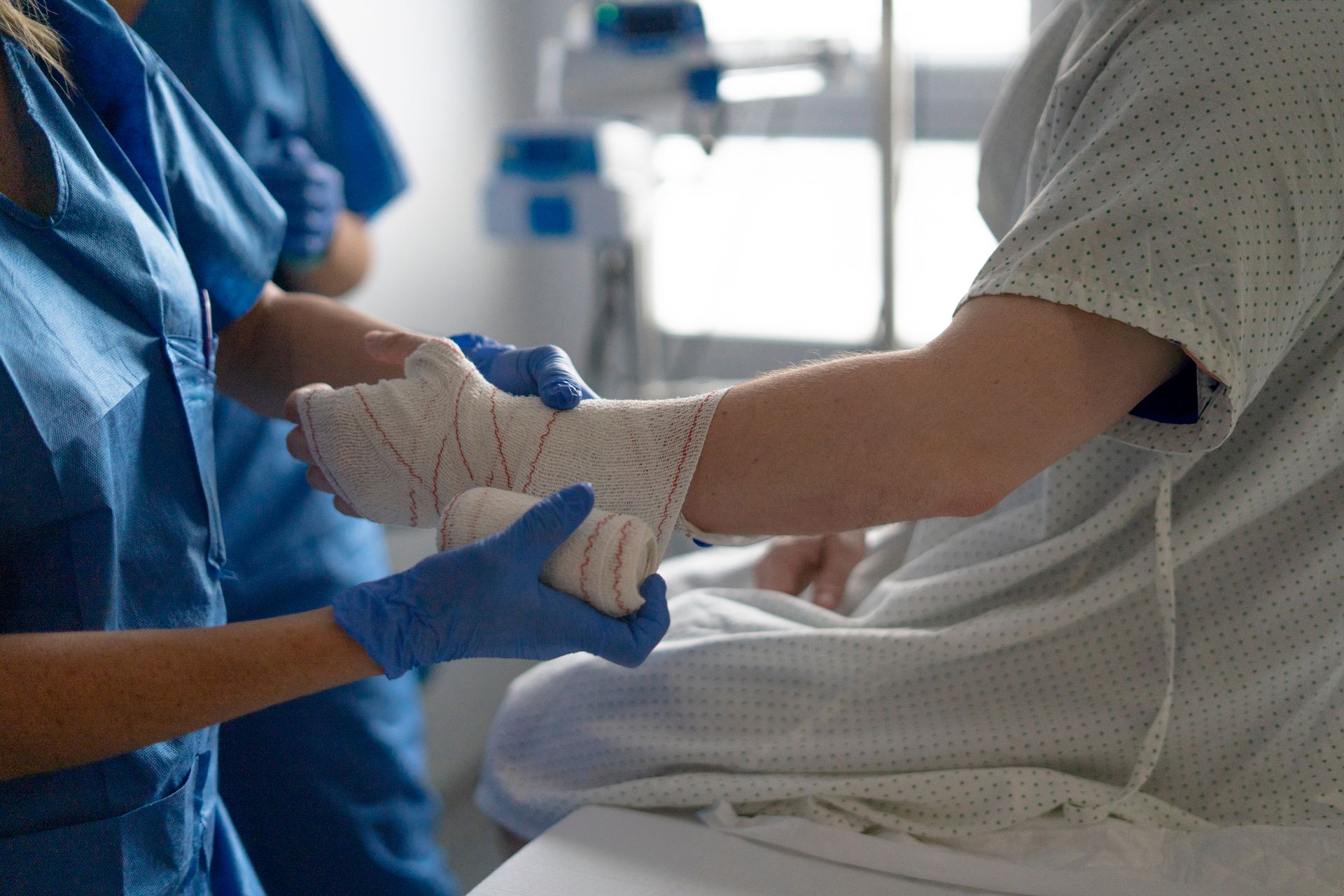 Infirmière enveloppant le poignet d'un patient dans un plâtre ; milieu hospitalier.