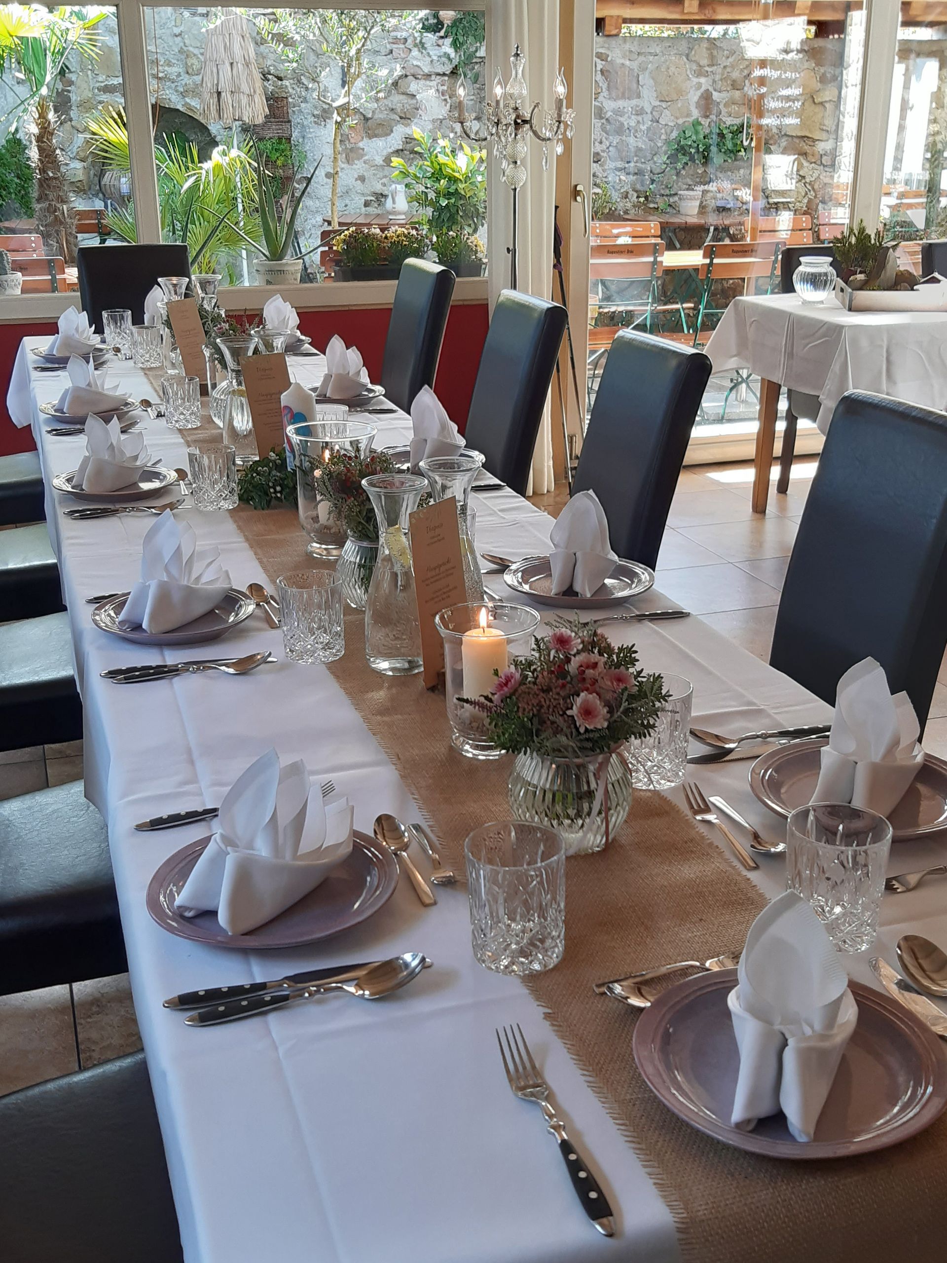 ein langer gedeckter Tisch mit weißen Tischdecken und Dekorationen